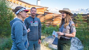 Ranger talking to two visitors outside a Visitor Center