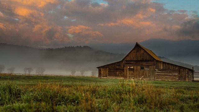 TA Moulton historic barn in the morning mist Teton Range beyond.