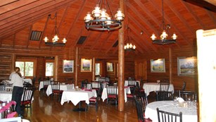 Multiple tables covered in table cloths in a log building.