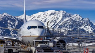 An airplane boards with mountains in the background.