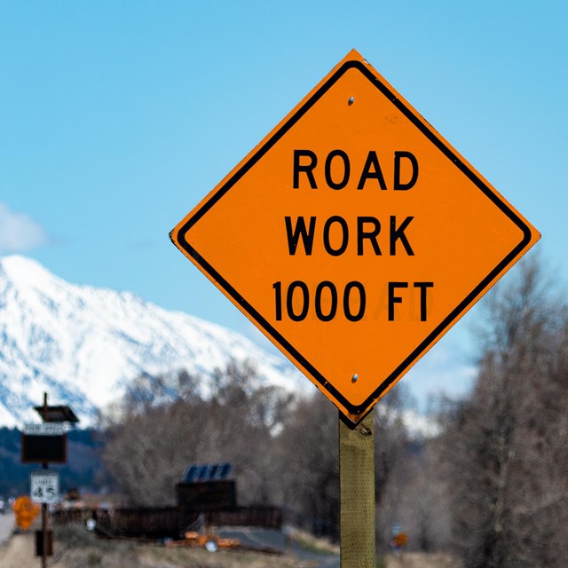 Road Work 1000ft orange sign with mountains in the background