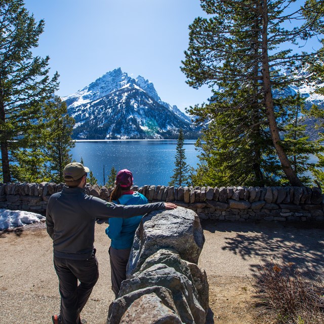 Two visitors enjoy the view of a lake from at an overlook