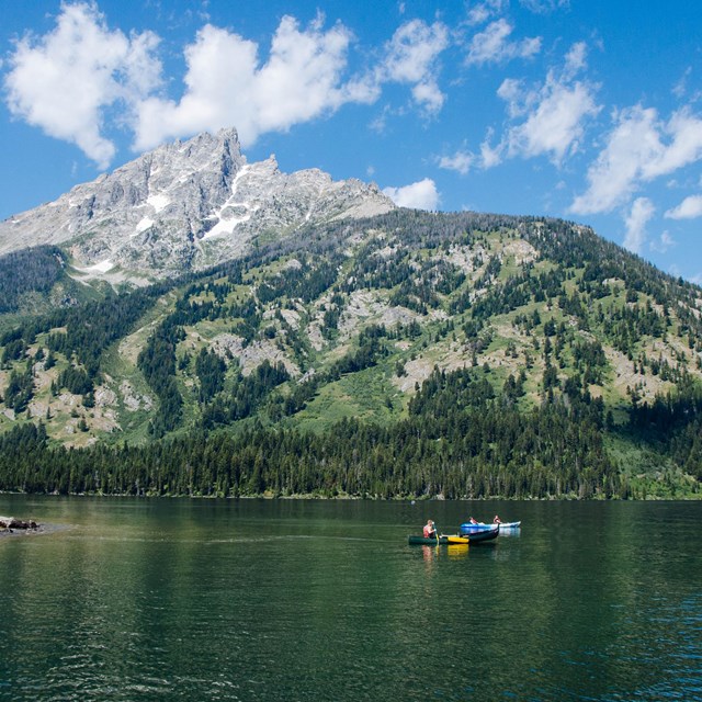 Boats on a lake at the base of a mountain.