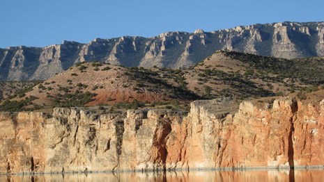 Two layers of vertical cliffs rise above a large lake.