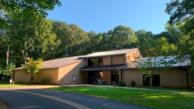 A tan colored brick visitor center with trees in the background