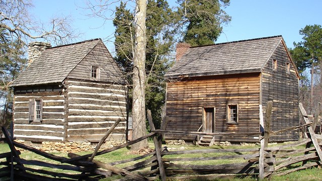 Two log houses and a split rail fence