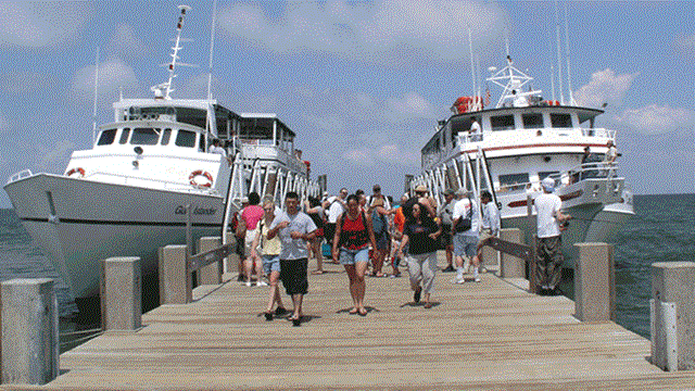 Visitors walk toward the camera down the dock at Ship Island.