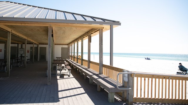 A wood pavilion overlooks a white sand beach.