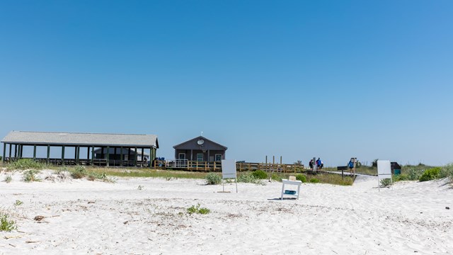 A picnic pavilion and concession store stand on a white sand beach.