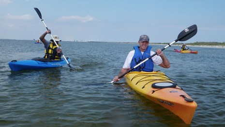 Kayakers paddle toward the camera.