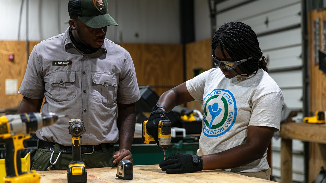 Members of the Youth Conservation Corps and their mentors stand in front of a table they built.