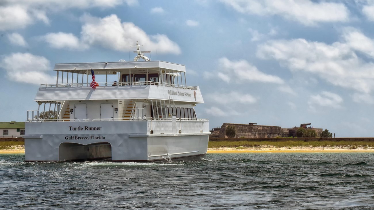 A ferry in the water pulling up to Fort Pickens.
