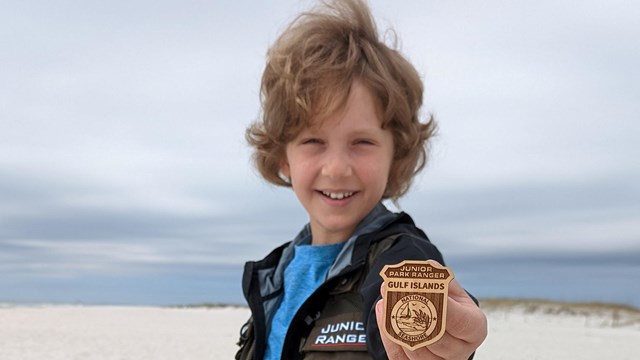 Kid holding up ranger badge