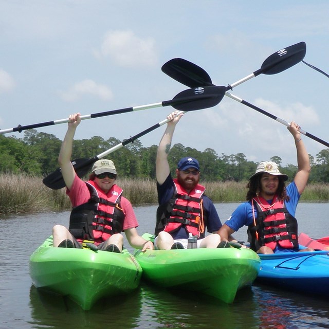 Kayaker raise their paddles in celebration