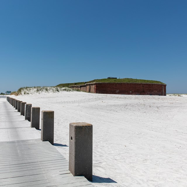 A pier on the beach leads up to a historic fort on a remote island.