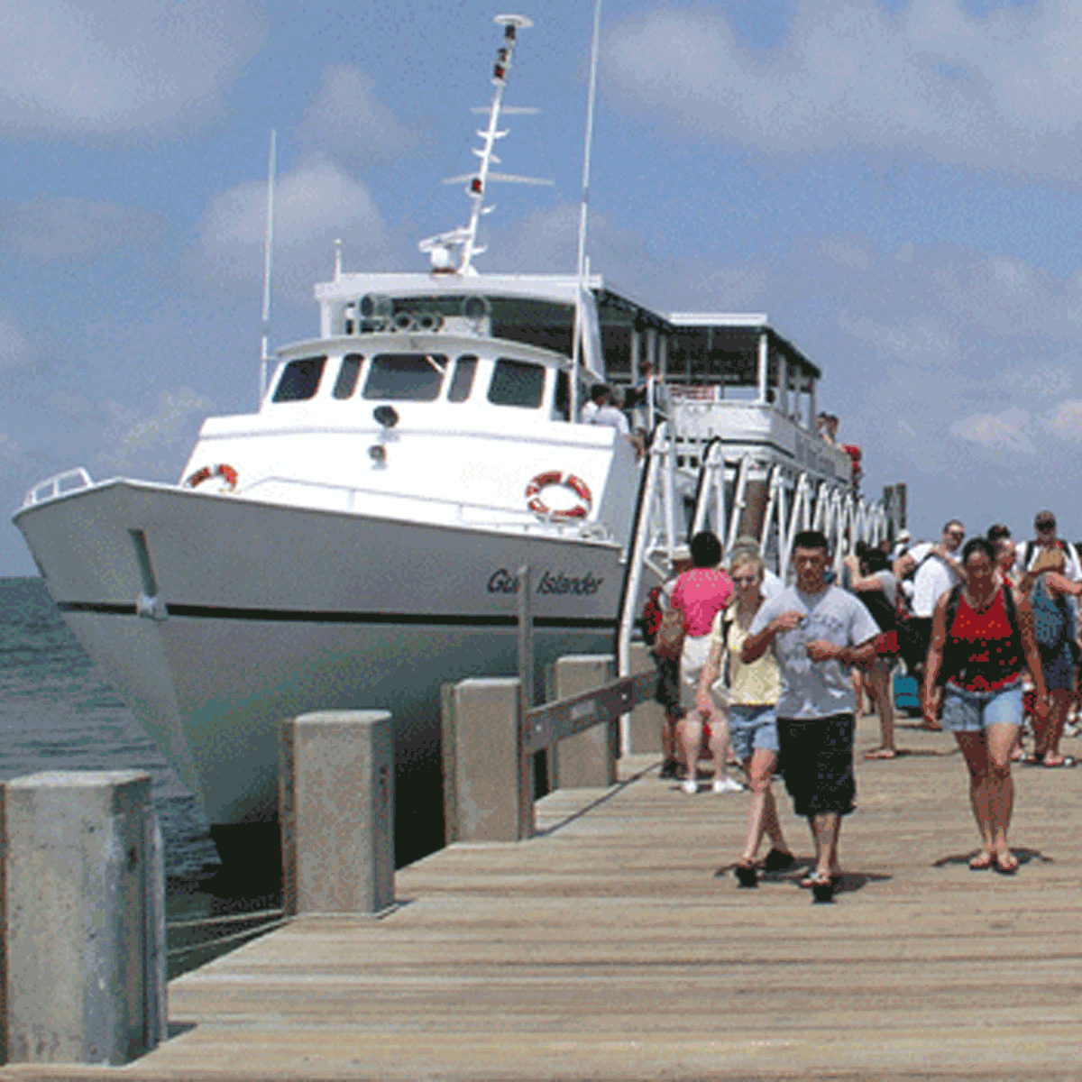 Visitors walk toward the camera down the dock at Ship Island.