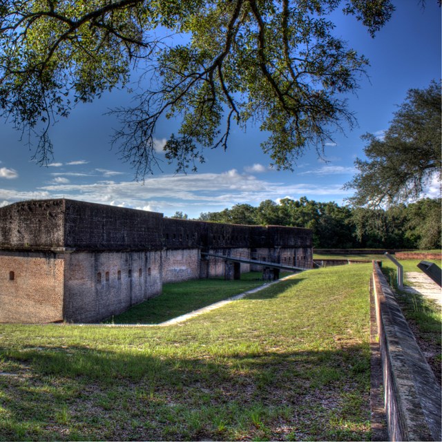 A masonry fort stands in a terraced field of grass.