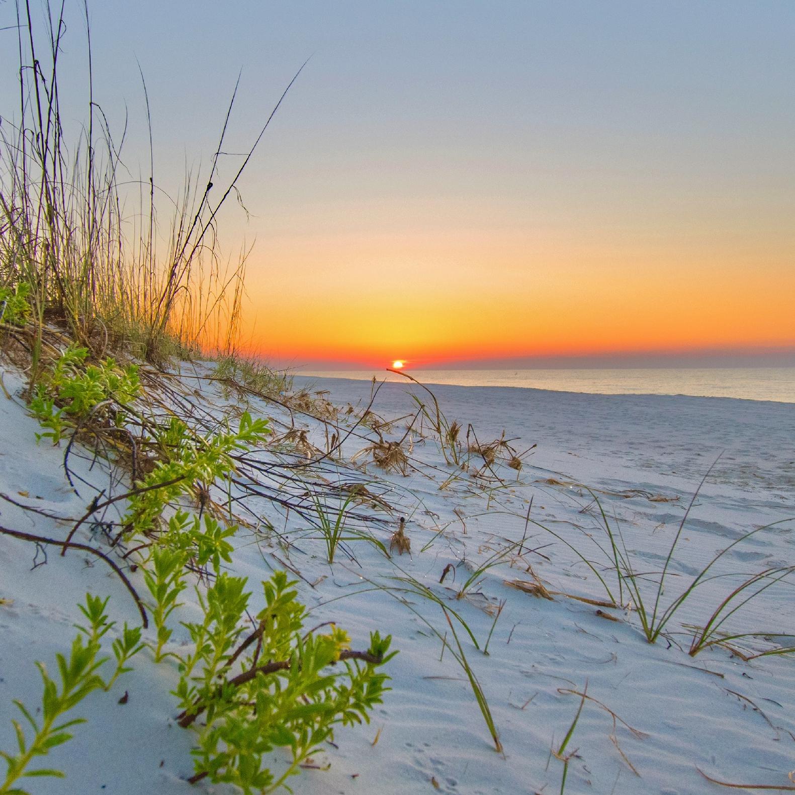 The sunrises over a white sand beach.