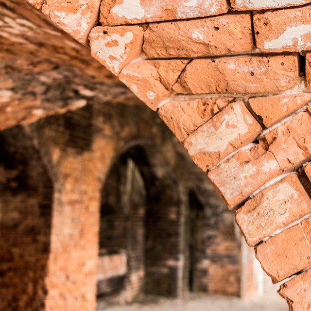 A close of photo of red weather-worn bricks forming part of an arch.