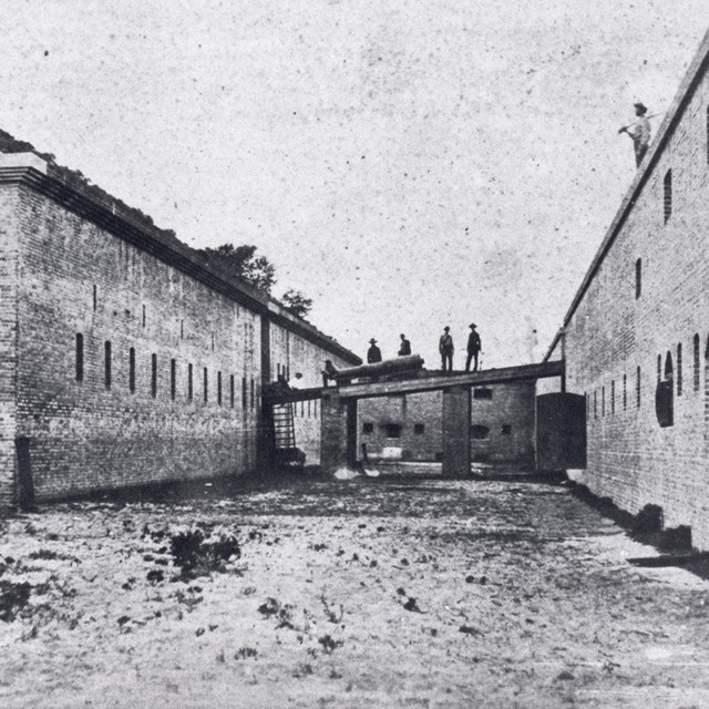 Historic image of soldiers moving a cannon across the drawbridge at Fort Barrancas.