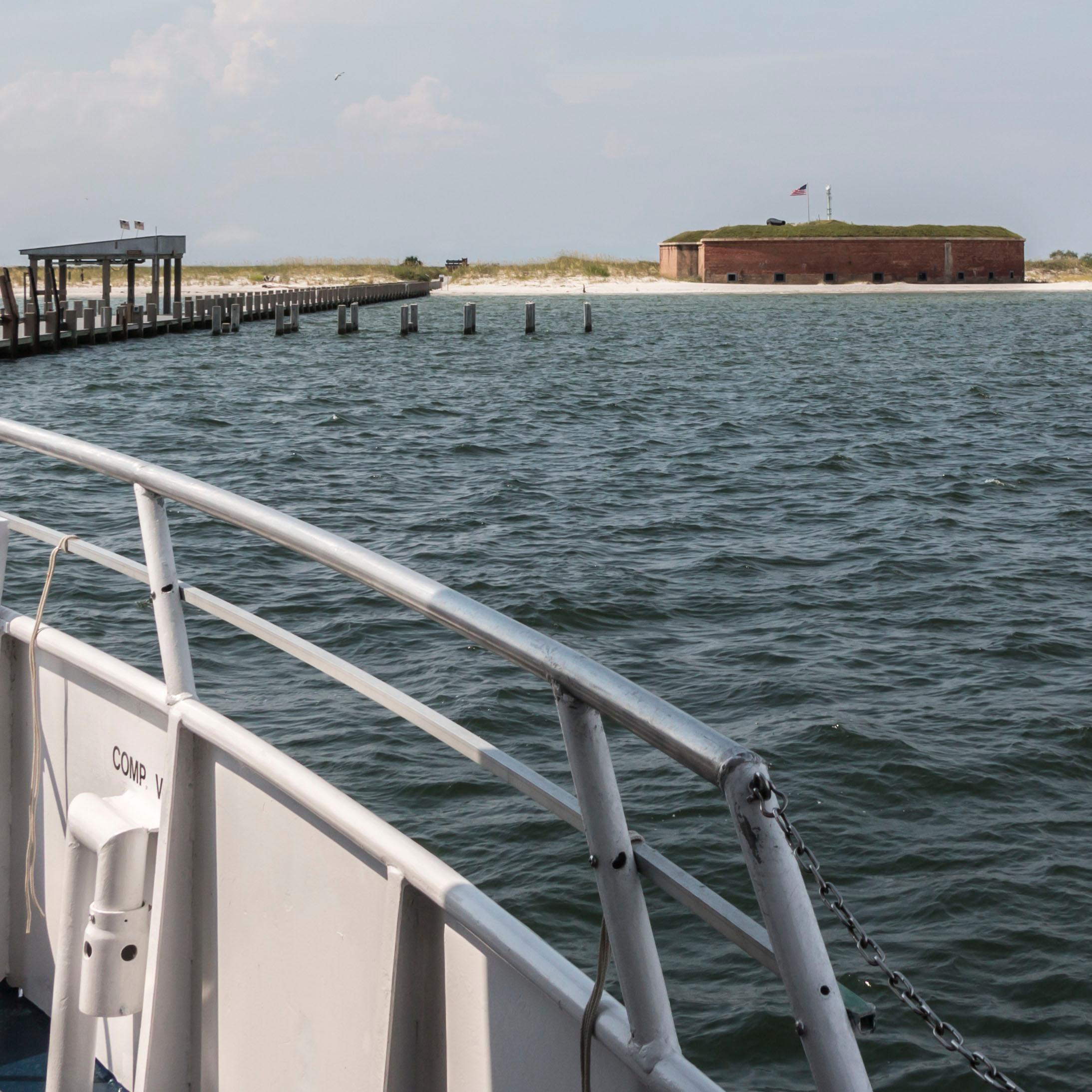 A ship approaches Ship Island, a historic fort stands on the island in a distance.