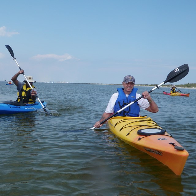 Kayakers paddle toward the camera.