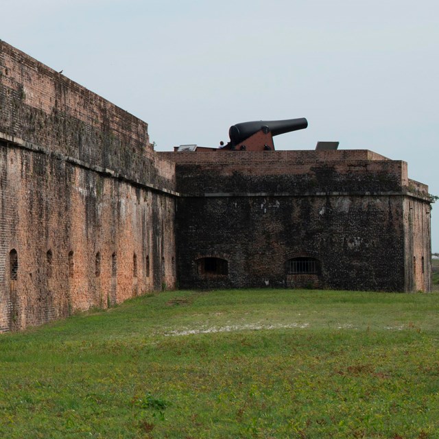 A brick fort at dusk, a cannon sits atop the walls