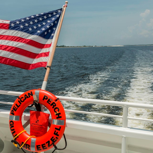 An American flag flies from the back of a tour boat.