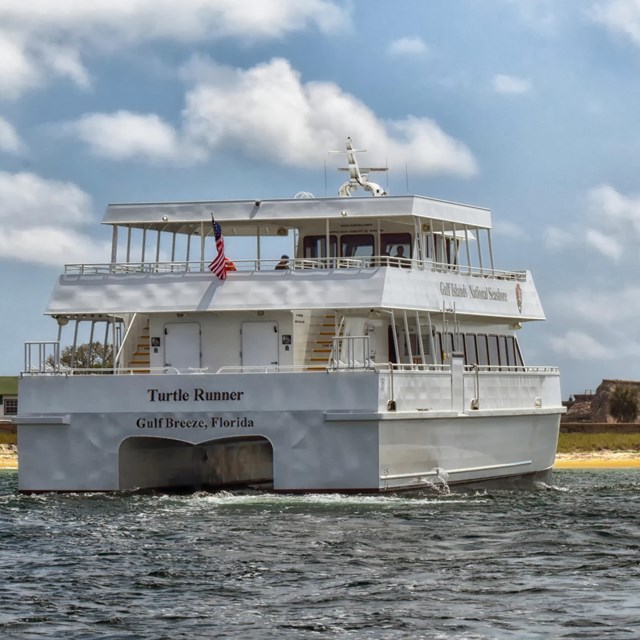 A ferry in the water pulling up to Fort Pickens.