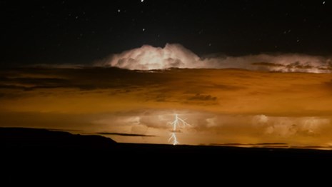 A nighttime thunderstorm is lit by lightning