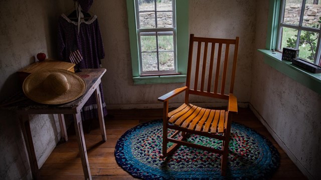 A chairs stands in a small room with a side table nearby