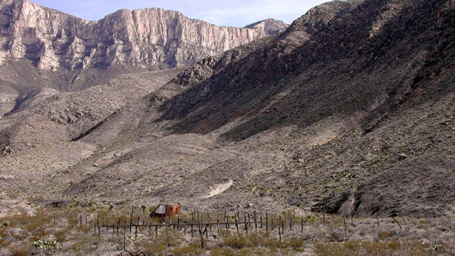 A small primitive corral stands below high desert mountains