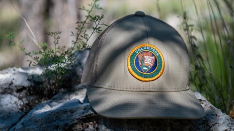 A brown baseball cap with a volunteer patch