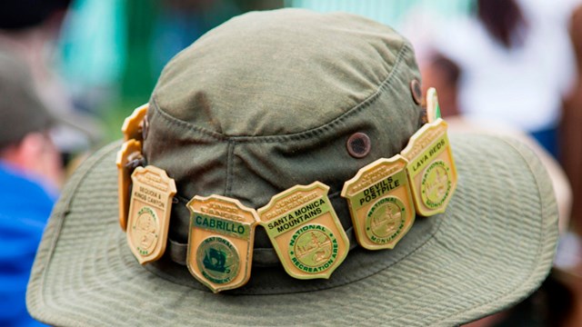 A junior ranger wearing a hat with several different junior ranger badges attached. 