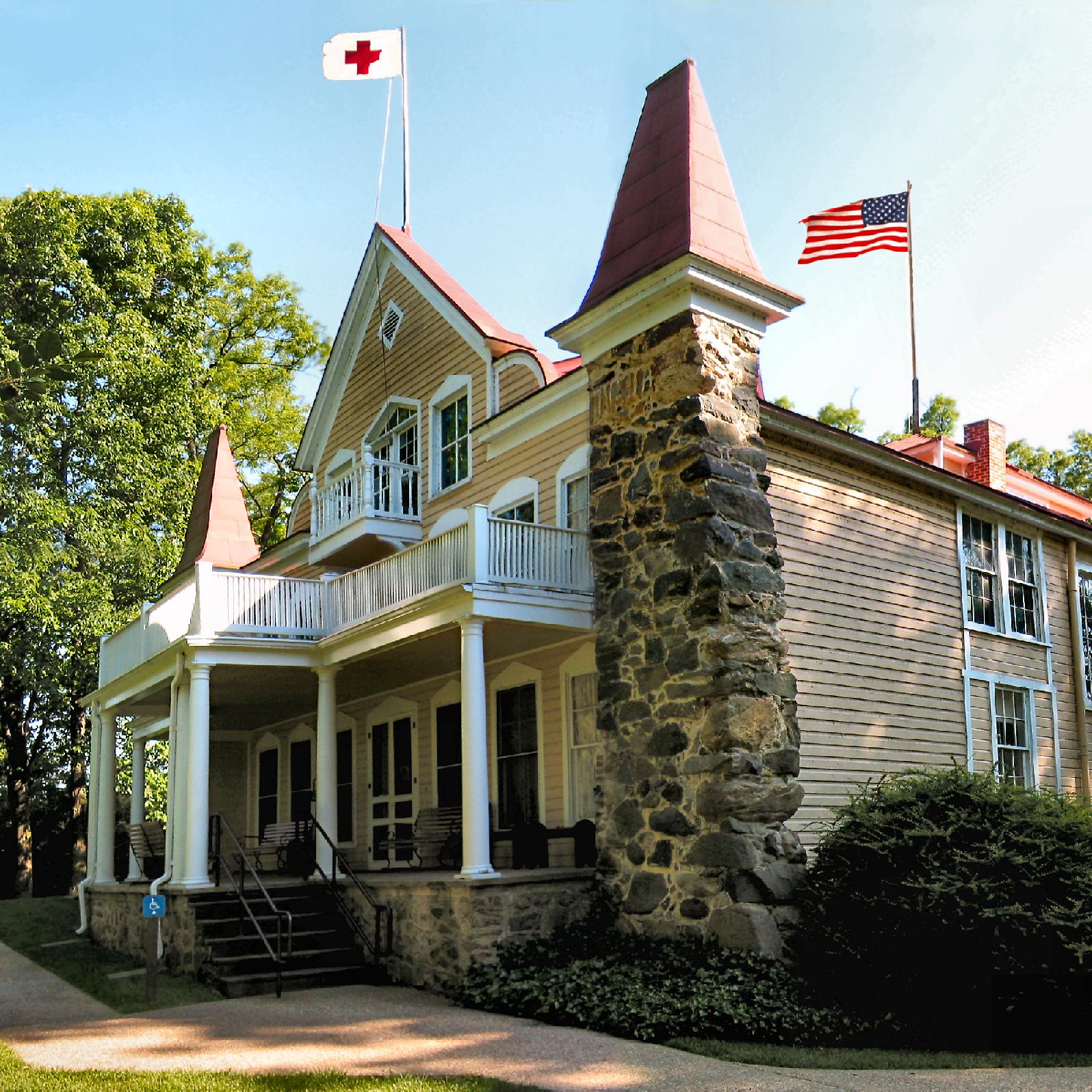 A stone and wooden home with a red cross flag flying.