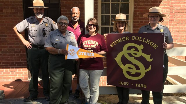 smiling group of rangers and people from partner organizations; they hold Storer College event items