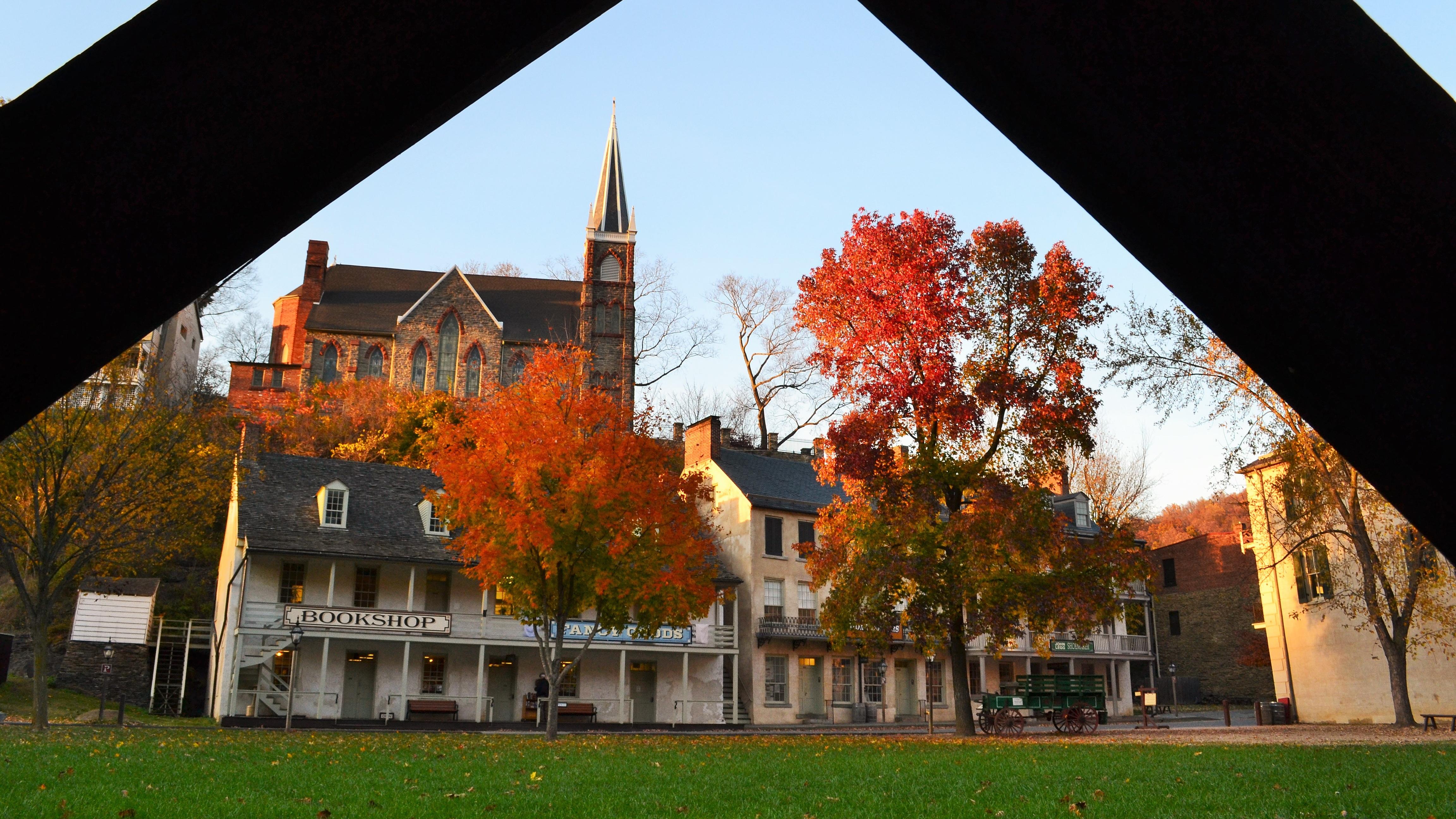 A view between two wooden beams of historic buildings in fall, with orange-colored leaves.