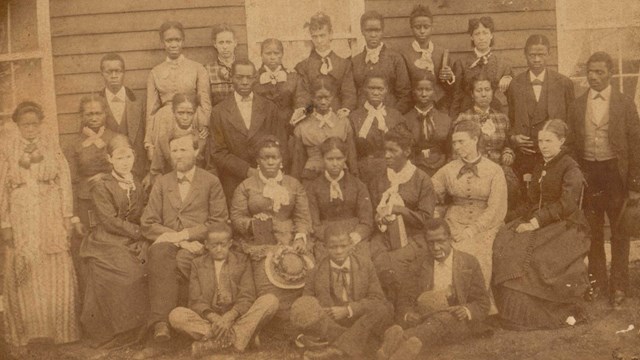 sepia tone image from the 1870s showing a group of African American students and their teachers
