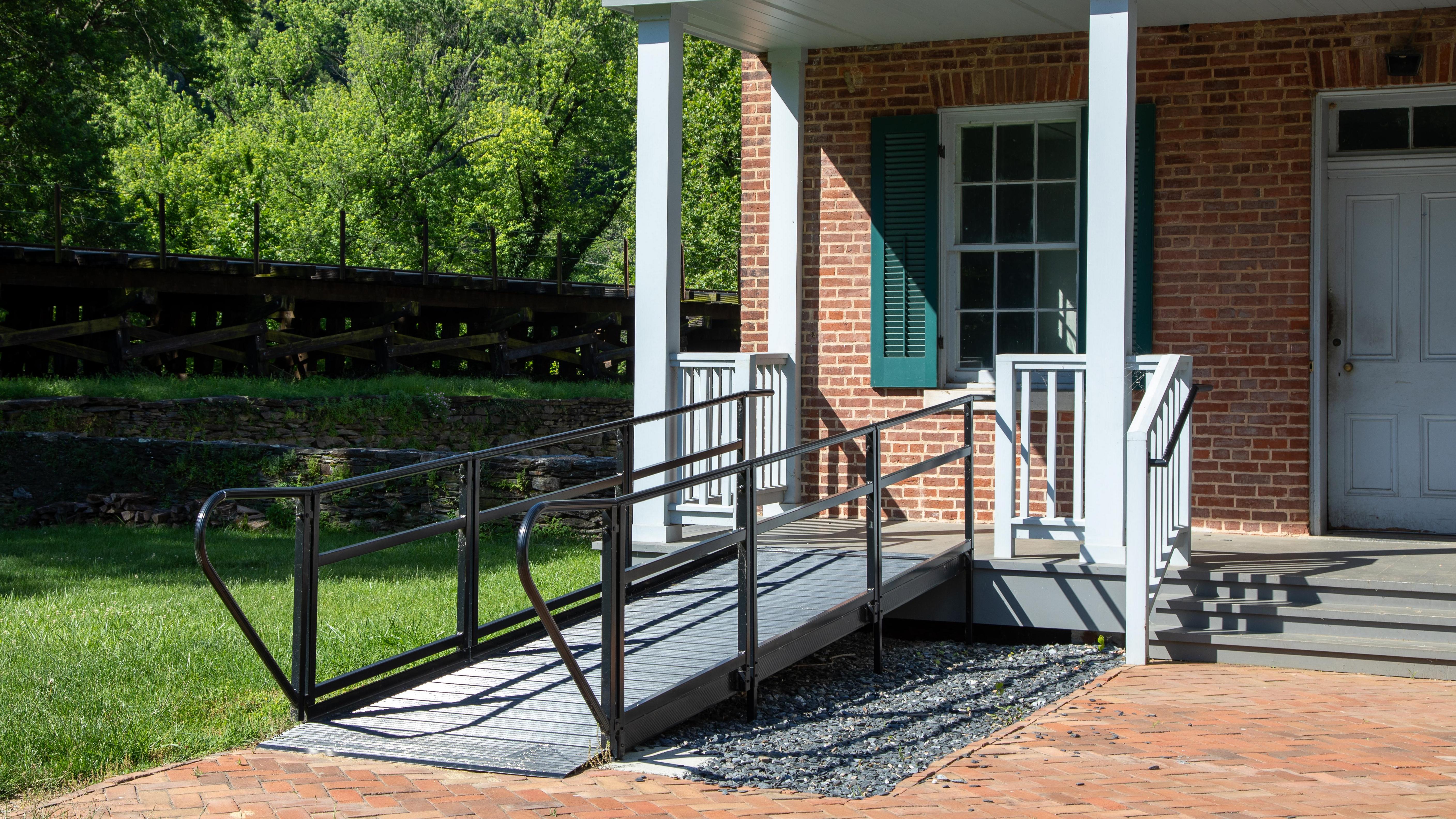 A ramp connects a brick path to the porch of a historic building.