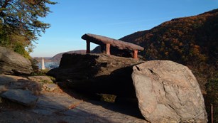 sun shining upon Jefferson Rock in the fall season; church steeple and mountain gap in background