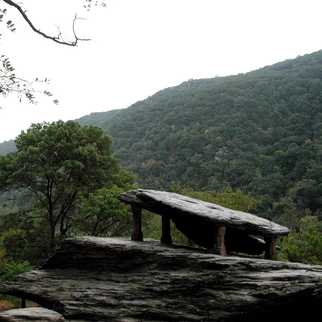 Slab of rock upheld by four pillars at a mountainous overlook