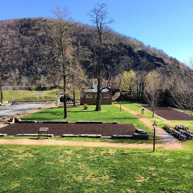 Two perpendicular rectangular areas marked with low walls in a grassy area