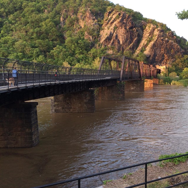 Pedestrian bridge across a river  connecting to a rocky cliff face