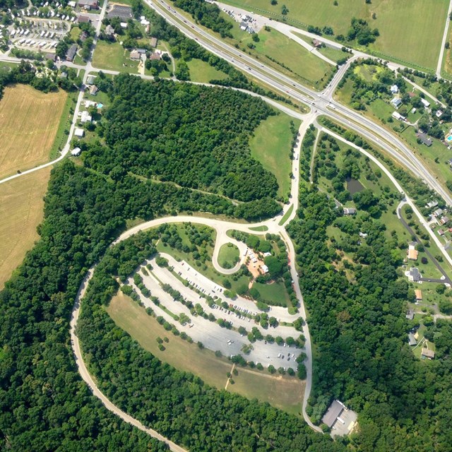 Aerial view of large paved parking area in wooded landscape
