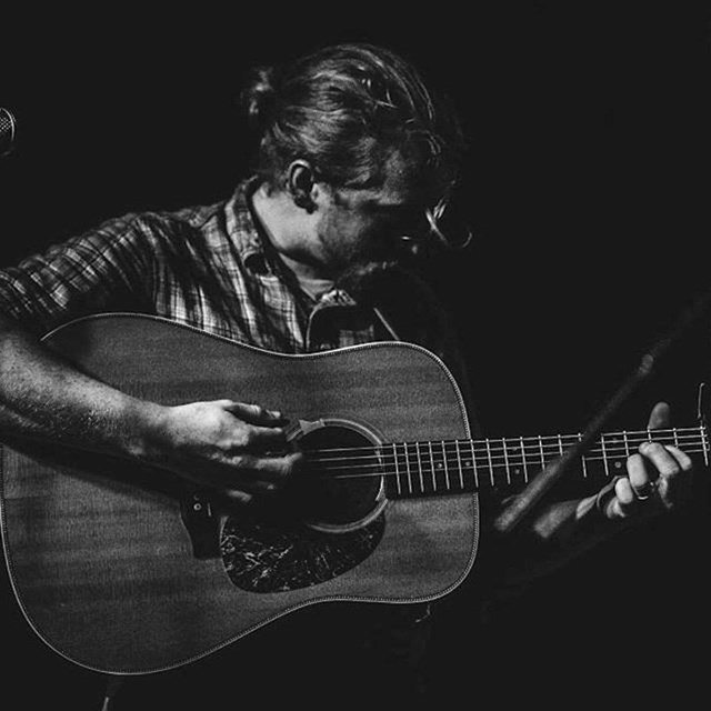 black and white photograph of Tyler Childers playing guitar; photo by Melissa Stilwell