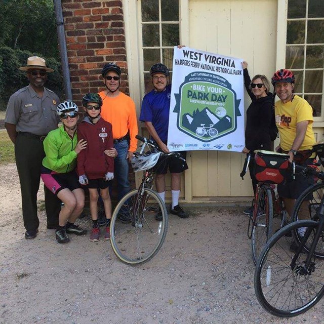 Group of people on bicycles in front of a brick building with a sign, 