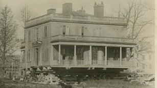 The Grange stands on wooden beams as it is prepared for moving in 1889.