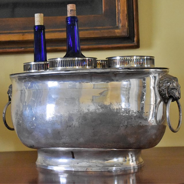 A silver wine cooler with wine bottles inside.
