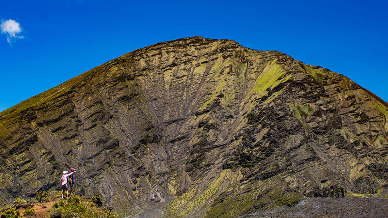 the crater of Haleakalā with two hikers looking out onto multiple colors visible in the cinder