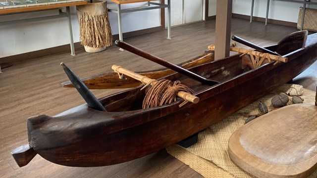dark wood canoe displayed in middle of visitor center